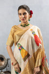 A close-up of the model wearing the Vanya Sarees off-white silk saree, highlighting a puppet motif on the shoulder.