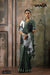 A full-length view of the model in Vanya Sarees' contemporary olive green linen cotton saree with a bold tropical print.