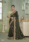 A full-length view of the model in Vanya Sarees' magnificent olive green saree with a heavy, multi-color embroidered cutwork border.