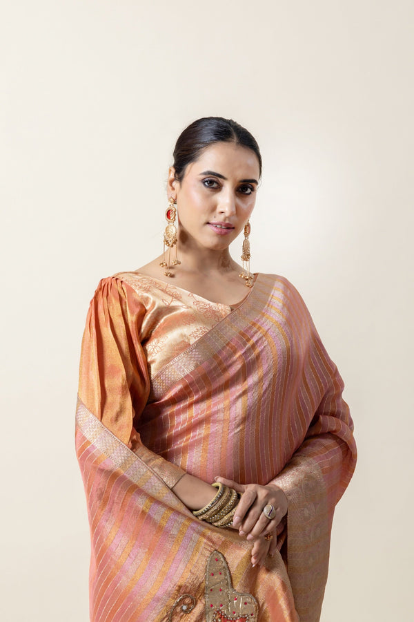A close-up of the model wearing the Vanya Sarees peach tissue silk saree, showing the texture and the puff sleeve blouse.