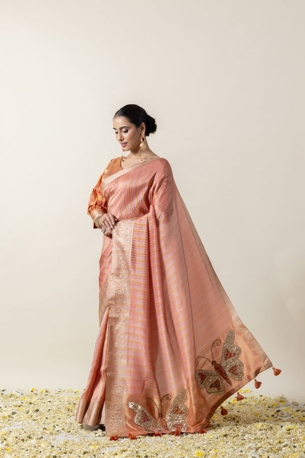 Model showcasing the beautiful fluid drape and flow of the Vanya Sarees peach tissue silk saree.