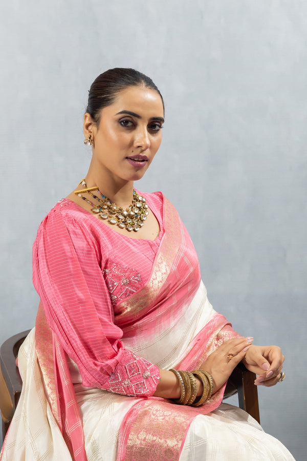 A close-up seated portrait of the model in a Vanya Sarees pink ombre saree, showing the embellished cuff of the bishop sleeve blouse.
