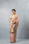 A full front view of the model looking at the camera in the Vanya Sarees pink tissue silk saree with a hand-embroidered blouse.