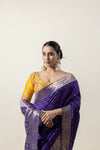 A close-up of the model in a Vanya Sarees purple Banarasi saree, highlighting the broad, intricate gold zari border and the embroidered blouse.