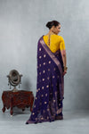 A full back view of the model in the Vanya Sarees ensemble, displaying the drape of the zari woven pallu and the yellow keyhole back blouse.