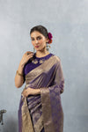 A close-up of the model in a Vanya Sarees purple silk saree, highlighting the rich Banarasi border and the embroidered collar of the blouse.