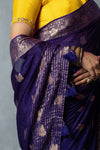 A detailed close-up of the pallu of the Vanya Sarees saree, showing the rich, woven gold zari and matching purple tassels.