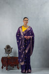 An graceful standing pose of the model in the Vanya Sarees purple and gold zari saree, perfect for a wedding or reception.