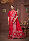 An elegant pose of the model showcasing the heavy gold zari and Meenakari border of the Vanya Sarees red bridal Banarasi saree.
