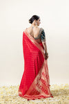 A full back view of the model showcasing the grand, sweeping pallu of the Vanya Sarees bridal red Banarasi silk saree.