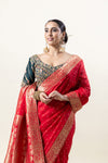 A close-up of the model in a Vanya Sarees red Banarasi saree, highlighting the broad, intricate gold zari border and the embroidered blouse.