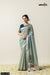 Full front view of a model in Vanya Sarees' elegant sage green linen silk saree with a navy blue designer brocade blouse.