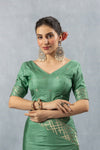 Front view of the model wearing a Vanya Sarees sage green designer blouse with a V-neck and geometric gold border on the sleeves.