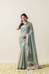 Model in an elegant pose wearing the Vanya Sarees sage green shimmer linen saree, perfect for festive occasions.