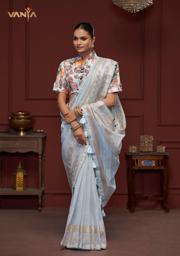 A full-length front view of a model wearing Vanya Sarees' sky blue linen silk saree, displaying the silver woven border and designer collar neck blouse.