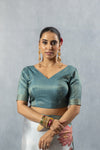 Close-up of Vanya's teal textured art silk V-neck blouse with short sleeves and bangles accessory.