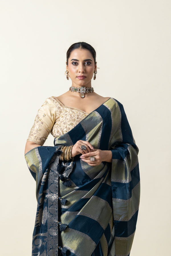 A close-up of the model wearing the Vanya Sarees teal and gold Banarasi saree, highlighting the ornate woven pallu and tassels.