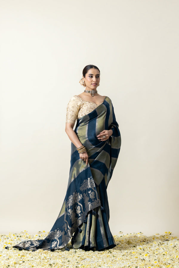 A full-length pose of the model showcasing the grand drape and woven pallu of the Vanya Sarees teal blue and gold Banarasi silk saree.