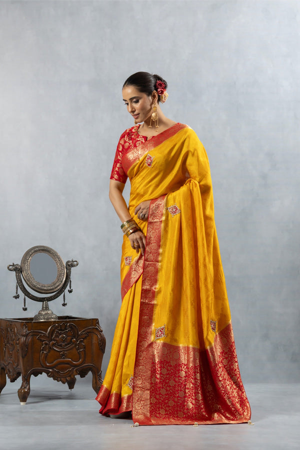 An elegant pose of the model showcasing the hand-embroidered buttis on the Vanya Sarees yellow Banarasi silk saree.
