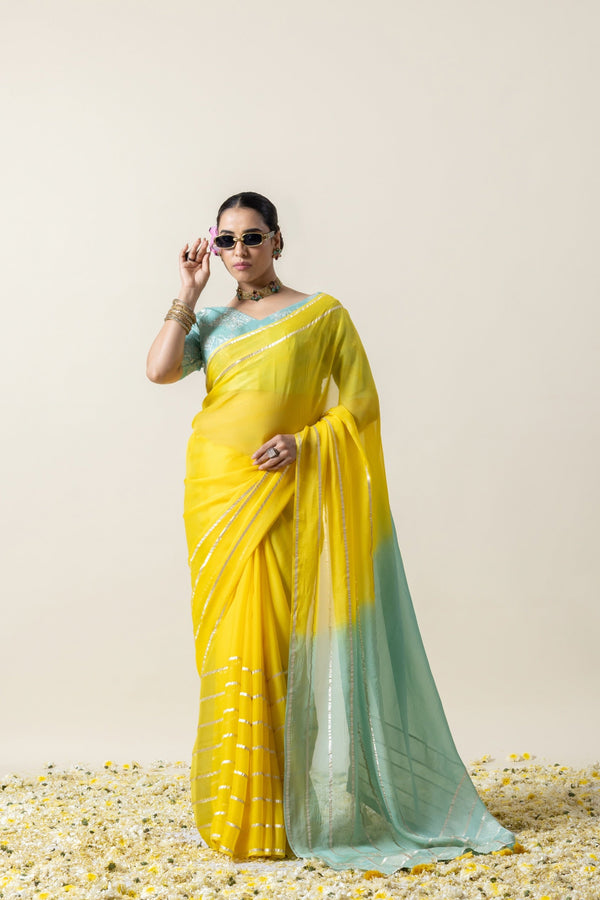 Model adjusting her sunglasses in a chic pose, showcasing the vibrant yellow body of the Vanya Sarees Gota Patti chiffon saree.