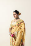A close-up shot of the model looking down while wearing the Vanya Sarees yellow linen saree, highlighting the lotus print and zari border.