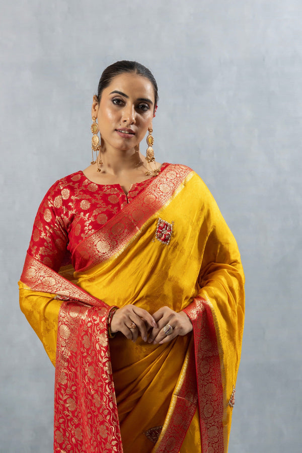 A close-up of the model in the Vanya Sarees yellow and red Banarasi saree, highlighting the rich border and brocade blouse.