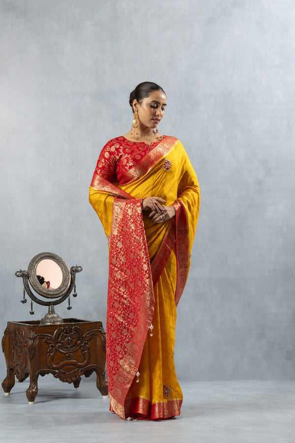Model showcasing the rich drape of the Vanya Sarees yellow Katan silk saree and its ornate red Banarasi pallu.